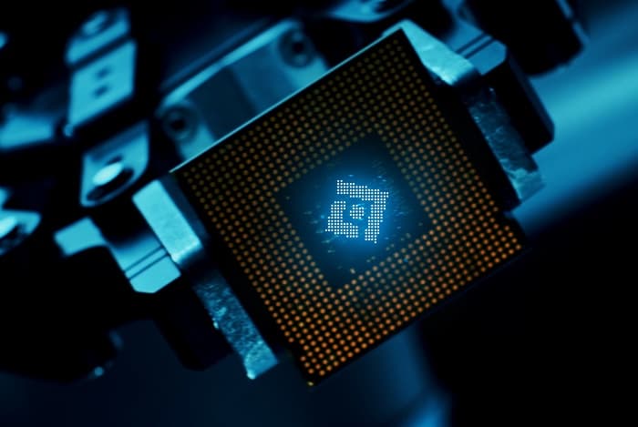 A processor held in a test fixture with the Code Metal mark glowing on its die