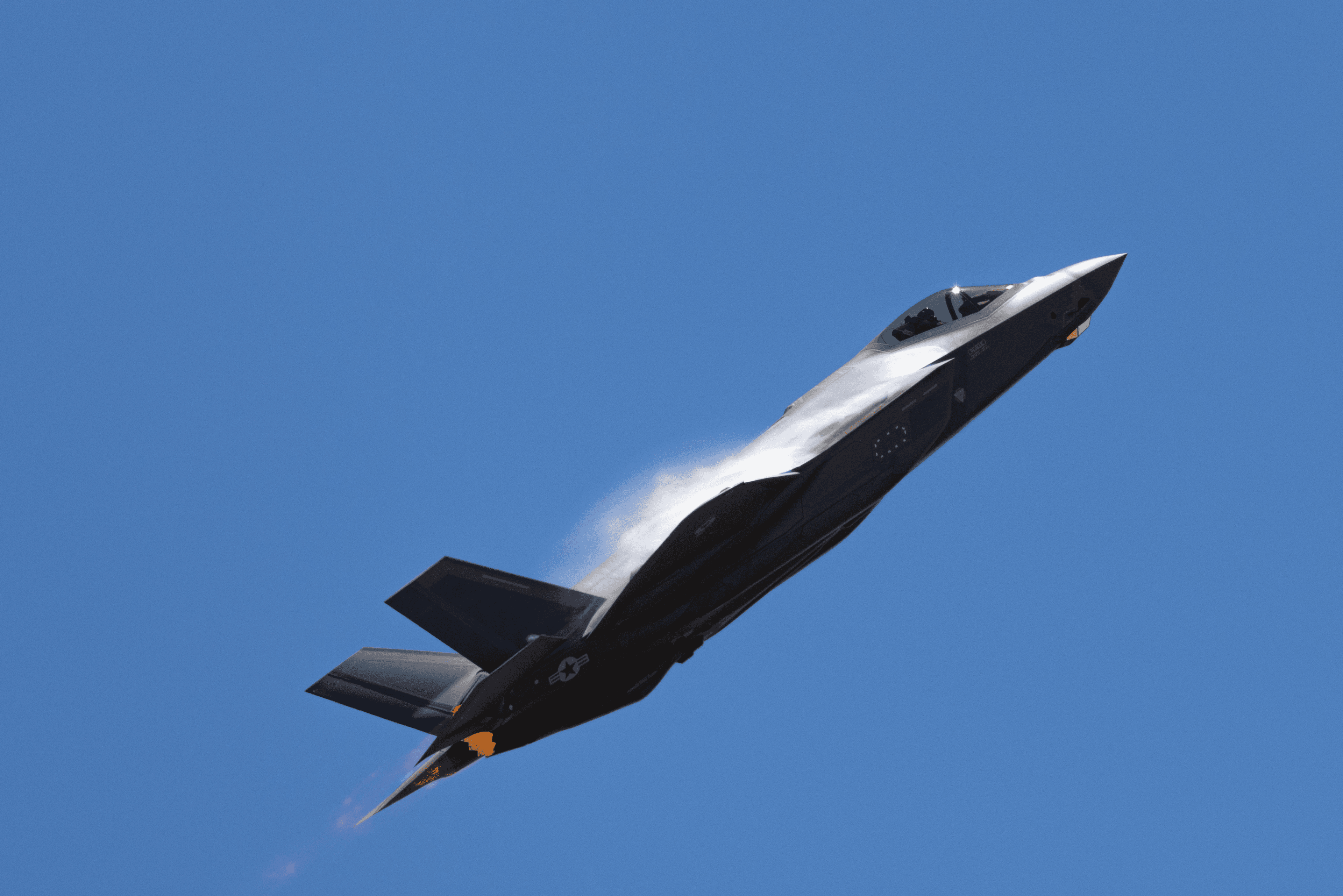 A fighter jet climbing against a clear blue sky